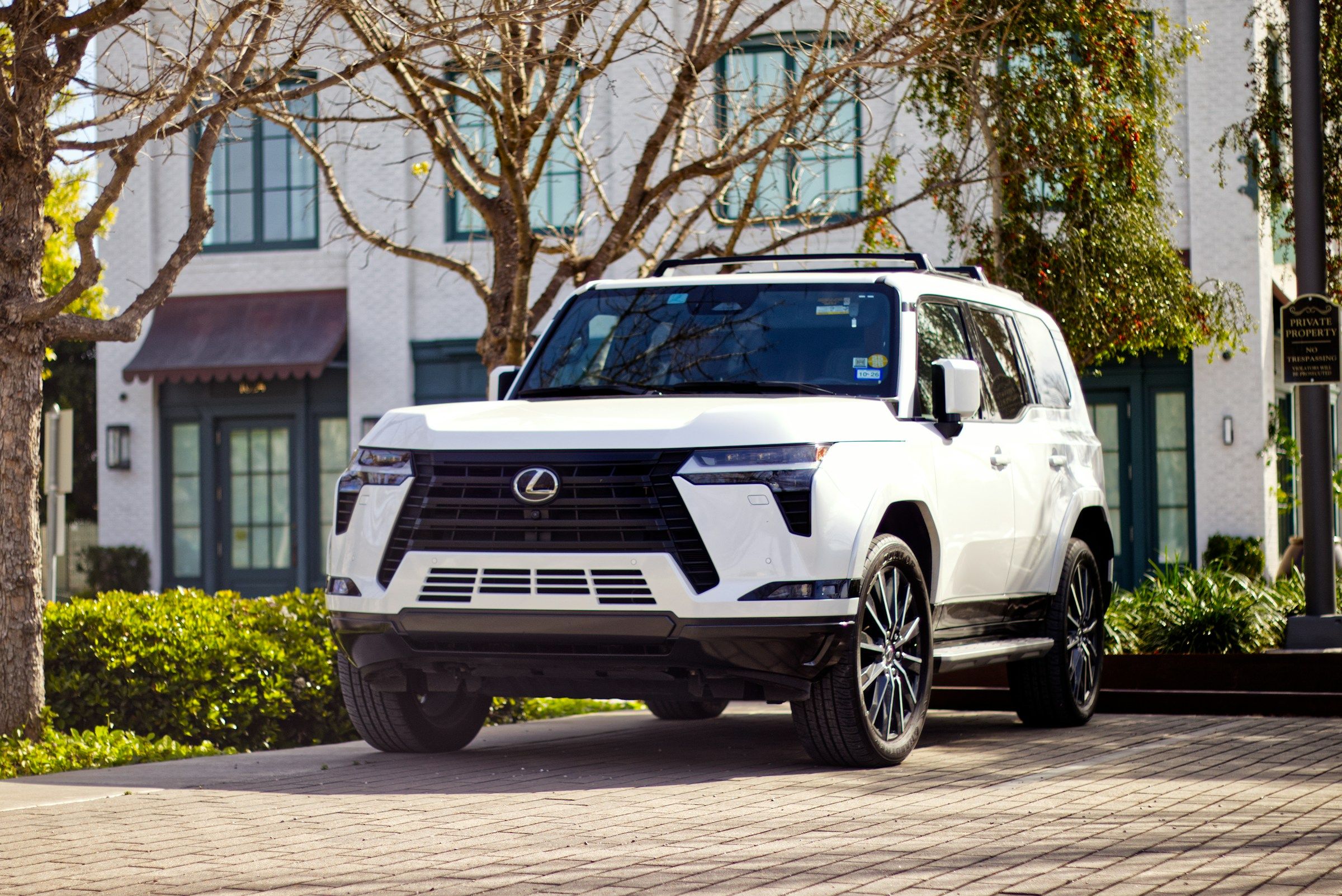White Lexus GX luxury SUV parked in front of a stately building